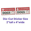 Two rectangular die-cut emergency pet identification stickers shown on a white background, with purple text below reading 'Die-Cut Sticker Size 2" tall x 4" wide.' The stickers are white with red borders and text, a white cross, and the word 'DOGS' in large black letters.